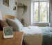 A bedroom hygrometer beside a bed with a slightly open window and soft daylight